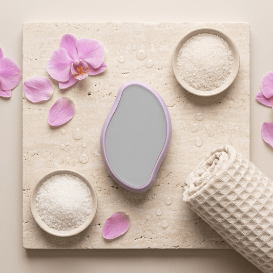 Épilateur cristal sans douleur sur un support en pierre, entouré de fleurs et de sels de bain.